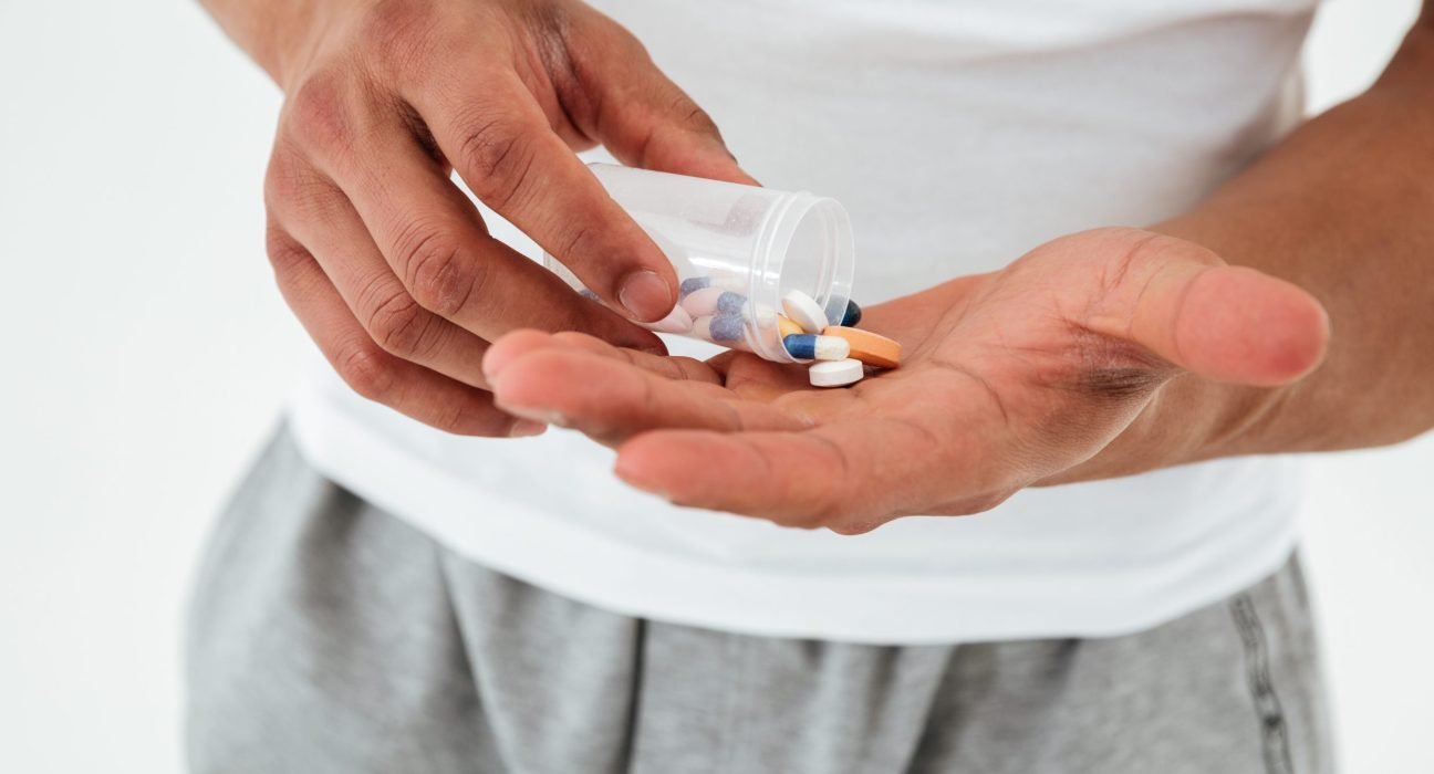 cropped-picture-young-sportsman-holding-vitamins-sport-pills-scaled-e1749025759134-1296x700